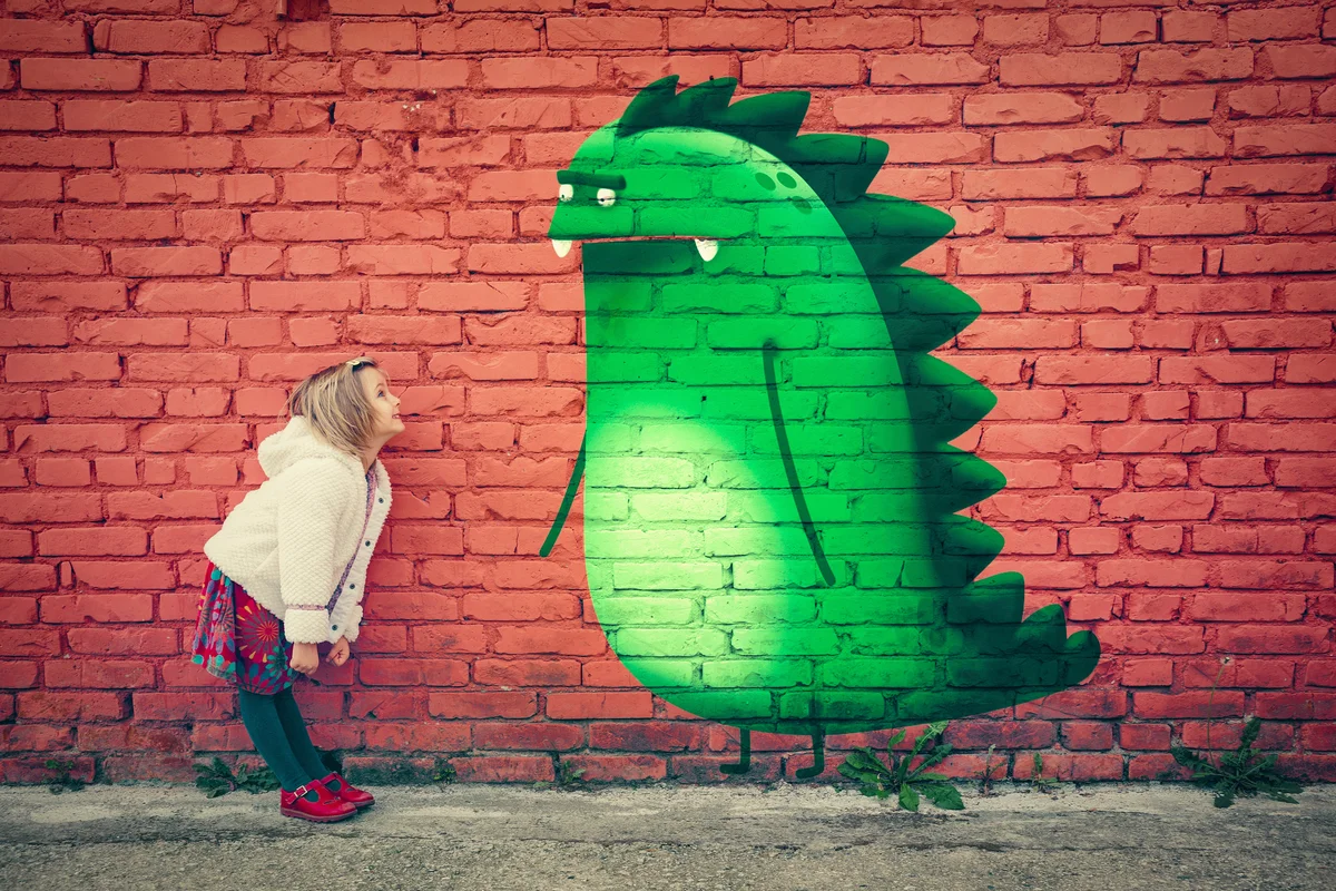 Young girl smiling to imaginary monster friend painted on wall