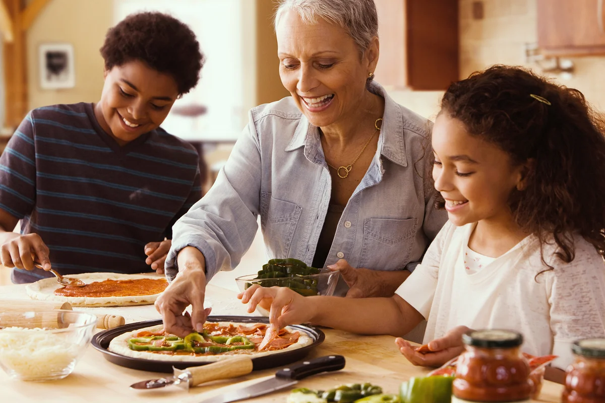 Grandmother and grandchildren making pizza