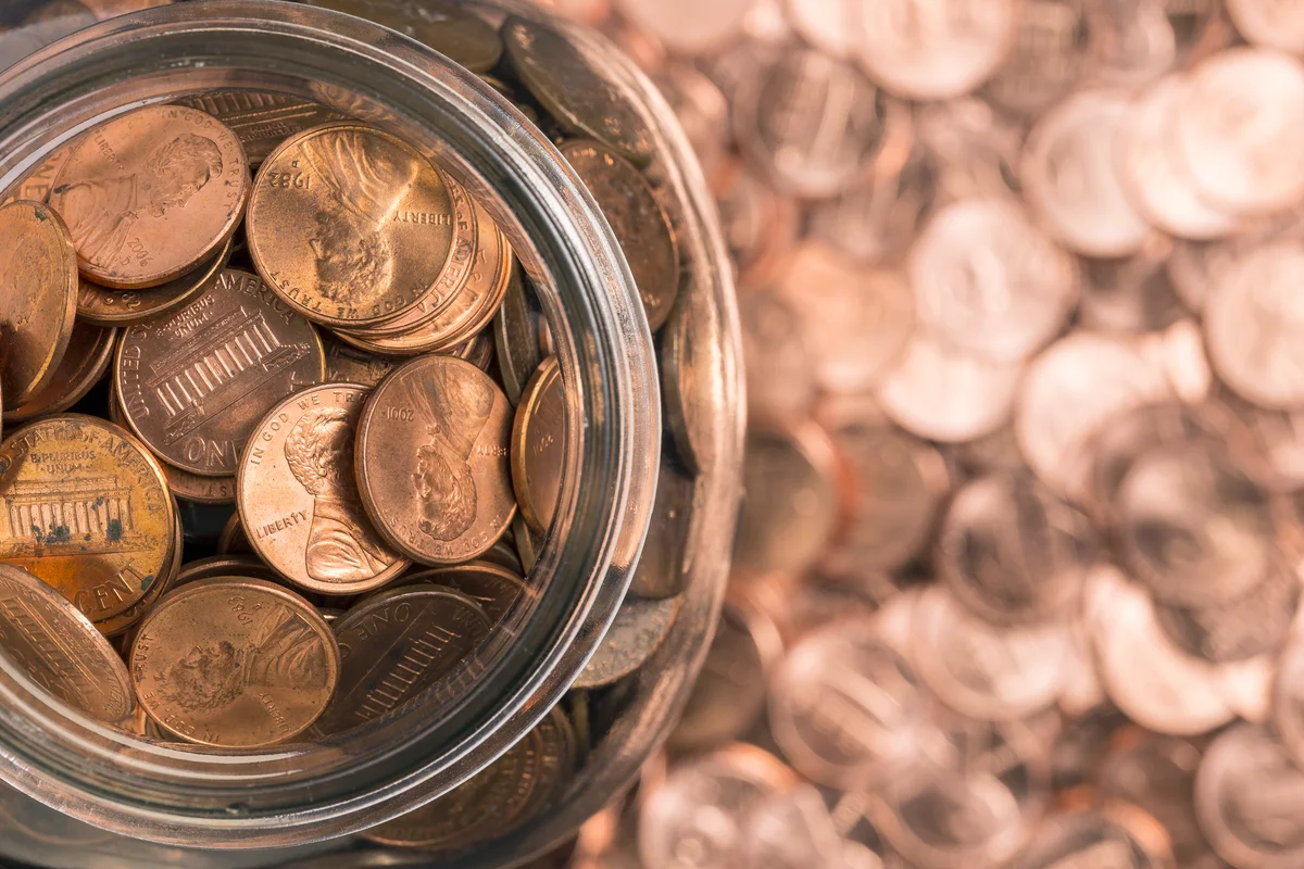 A jar of pennies surrounded by more pennies