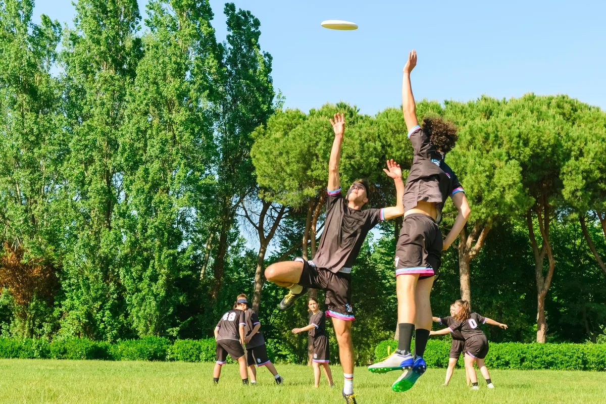 Teenagers people in team wear playing a frisbee game in park