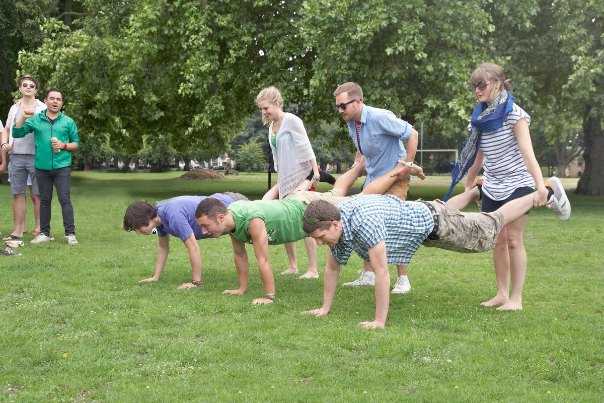 A group of friends playing wheel barrow race