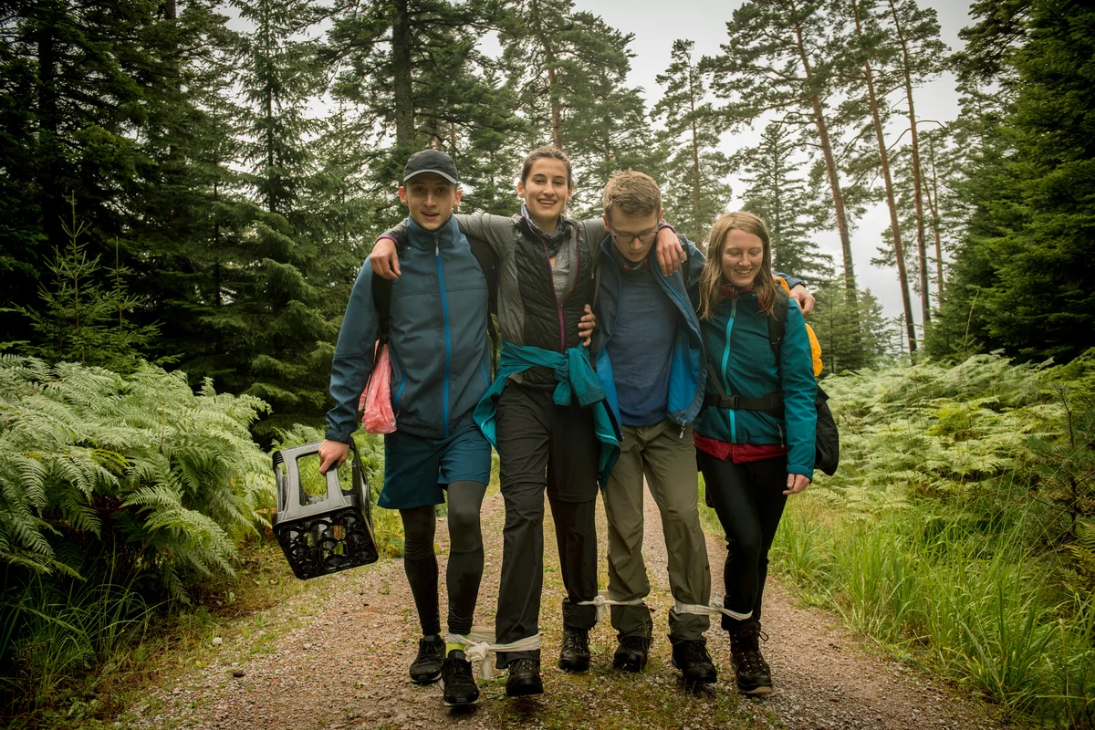 Teenagers enjoy three legged race in forest