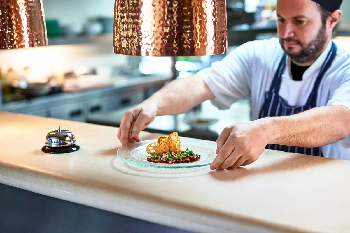 Chef placing plate of food on service counter