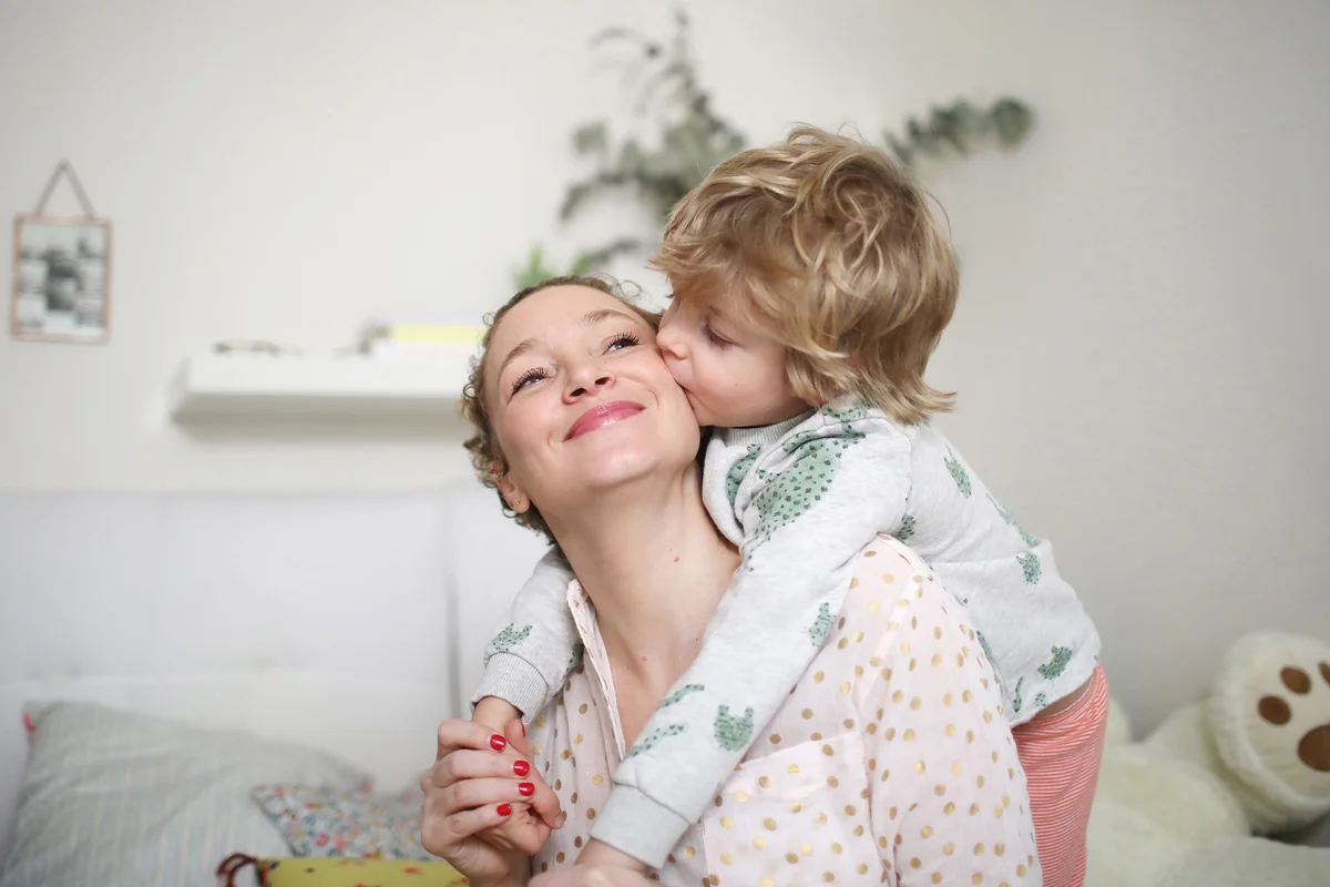 A little boy taking his mum in his arms in the bedroom