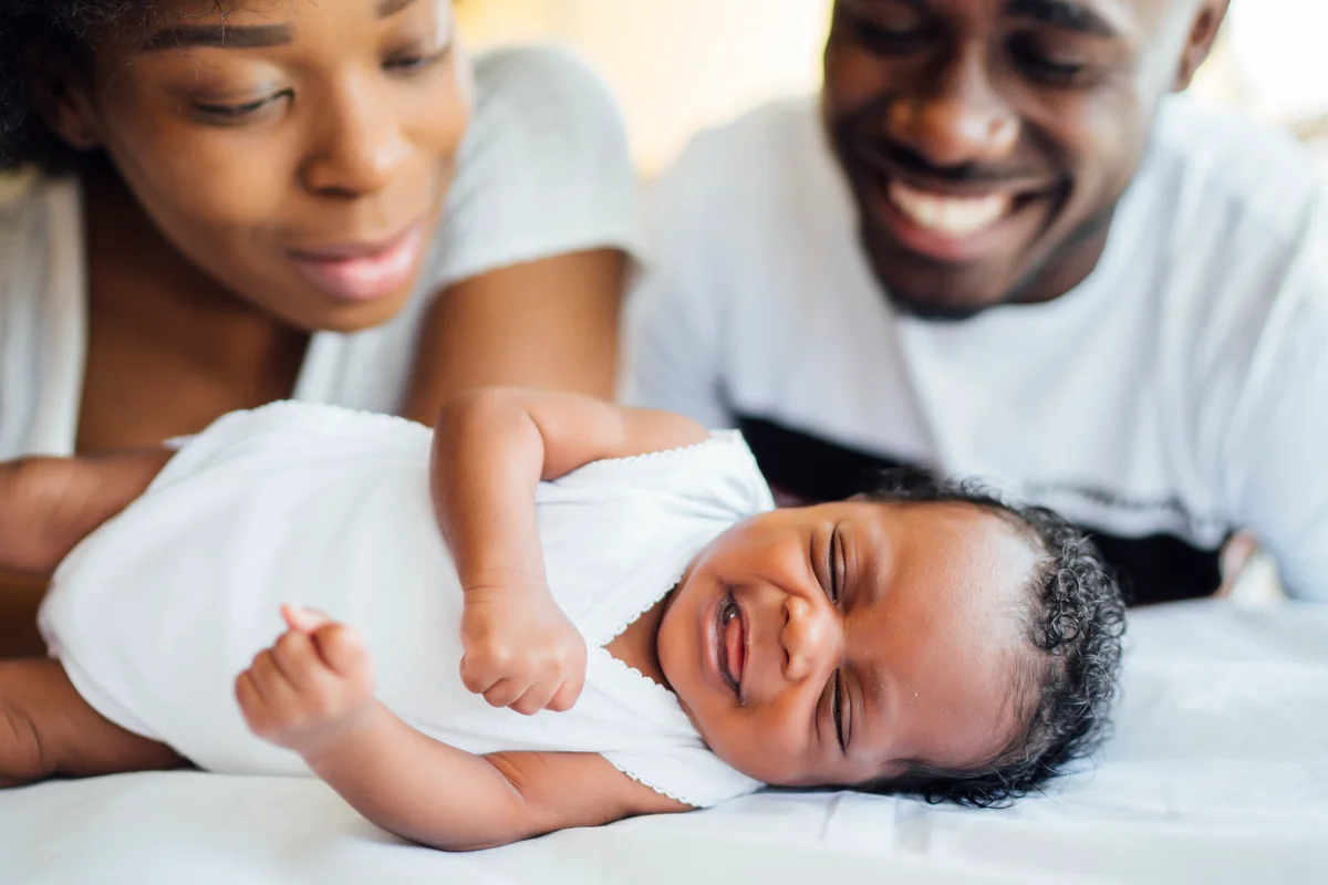 parents looking at smiling infant daughter