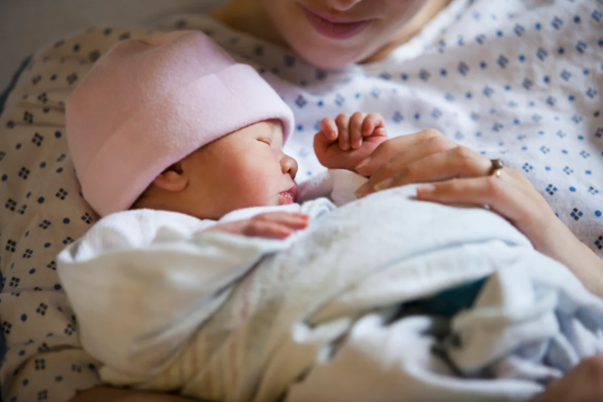 mother holding infant daughter at hospital