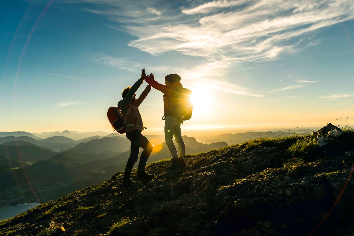 Cheering couple reaching mountain summit