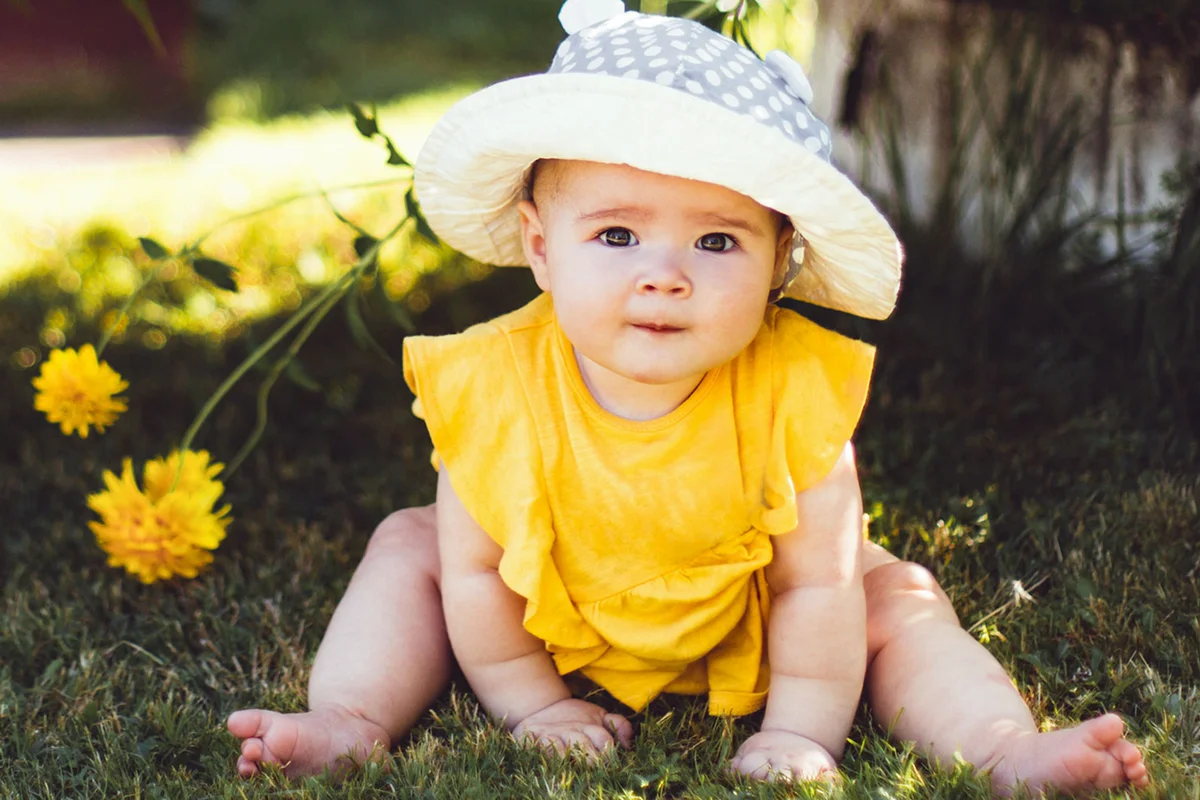 baby girl sitting on grass with flowers