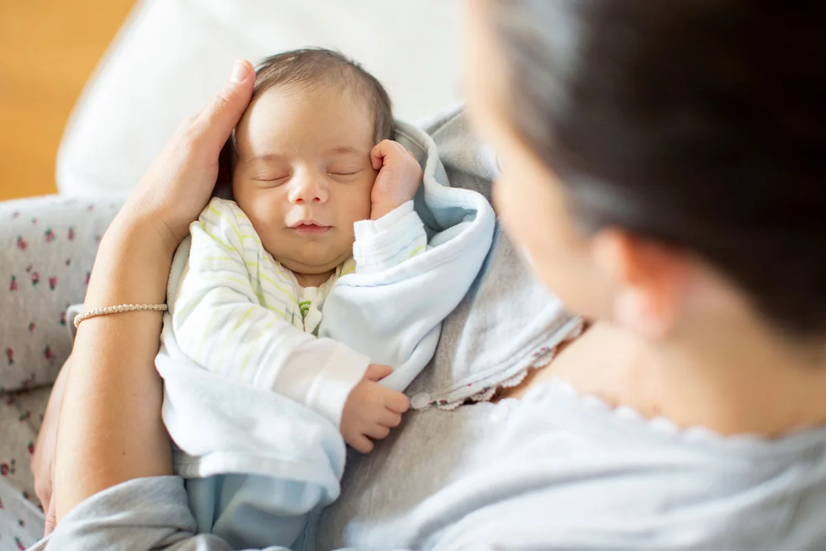 baby sleeping in mother's arms listening to music