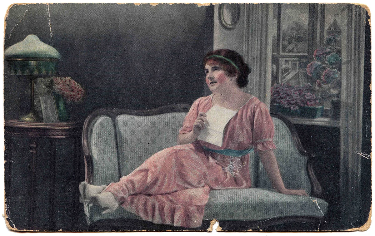 Woman sitting on the couch, dreamily presses to her bosom a love letter | Getty Editorial Use