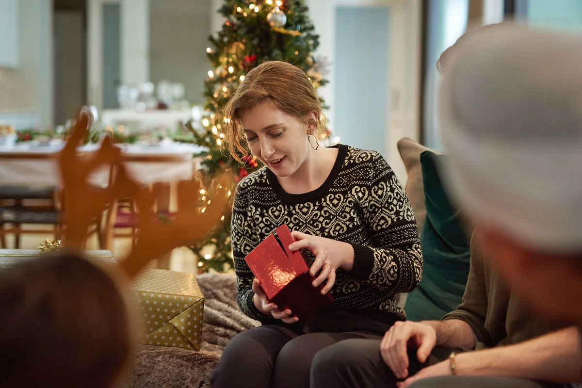 woman opening gift a white elephant Christmas party