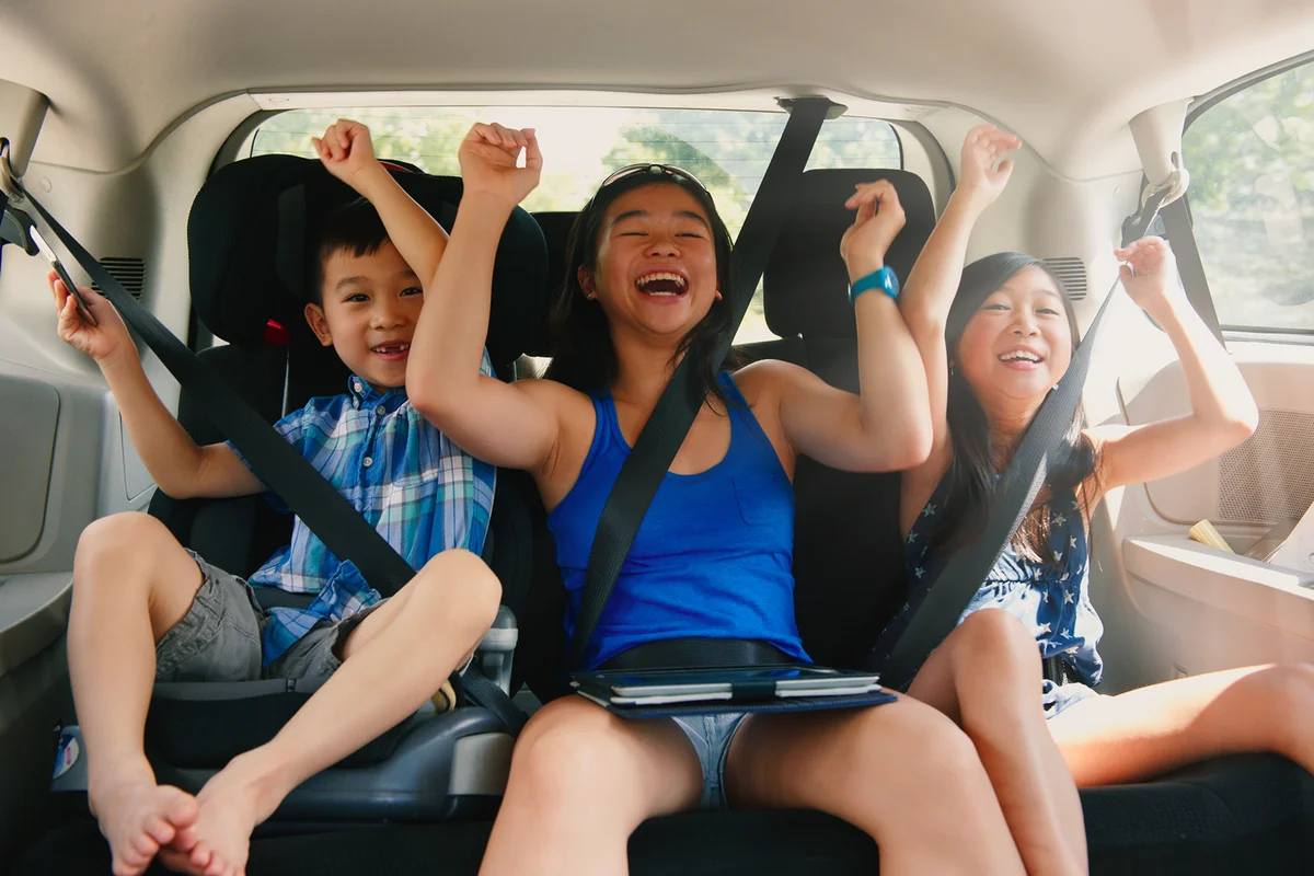 children cheering in backseat of car