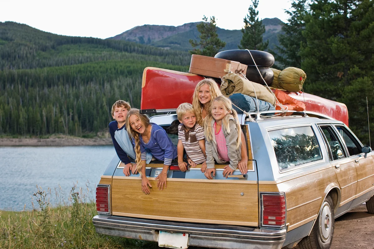 Kids hanging out of back of station wagon