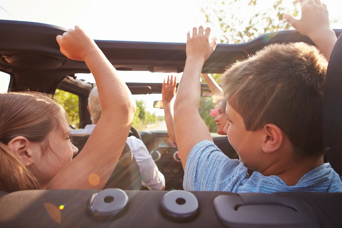 Grandparents Taking Grandchildren On Trip In Open Top Car