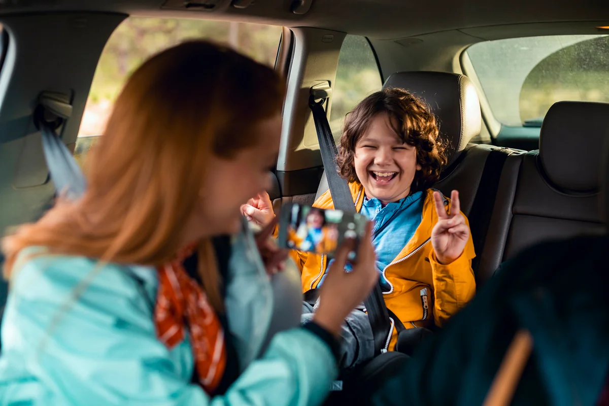 Close up of a mother taking a picture of her son in the backseat