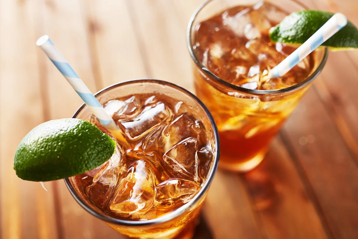 Two Glasses of Long Island Iced Tea Lime Wedges on Wooden Table Top