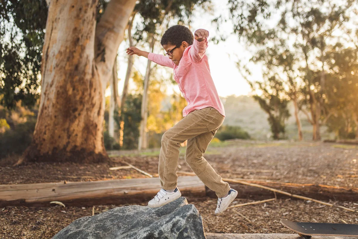 Side view of boy jumping on rock in forest