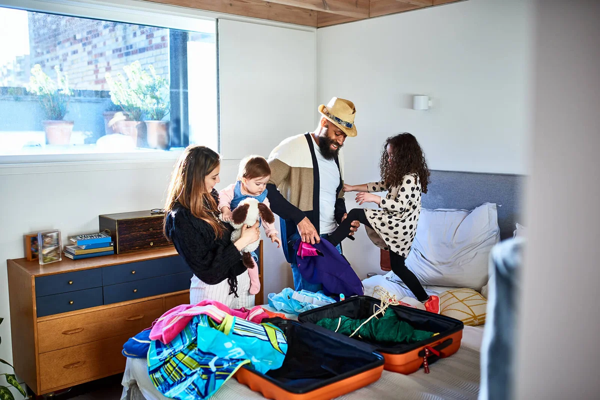 Parents and two daughters packing suitcase for vacation
