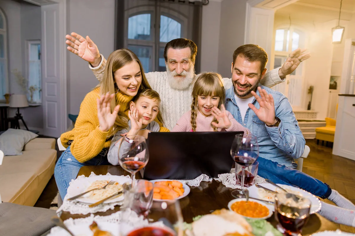 Beautiful family, sitting at the table with dinner meal, smiling, happy and using laptop