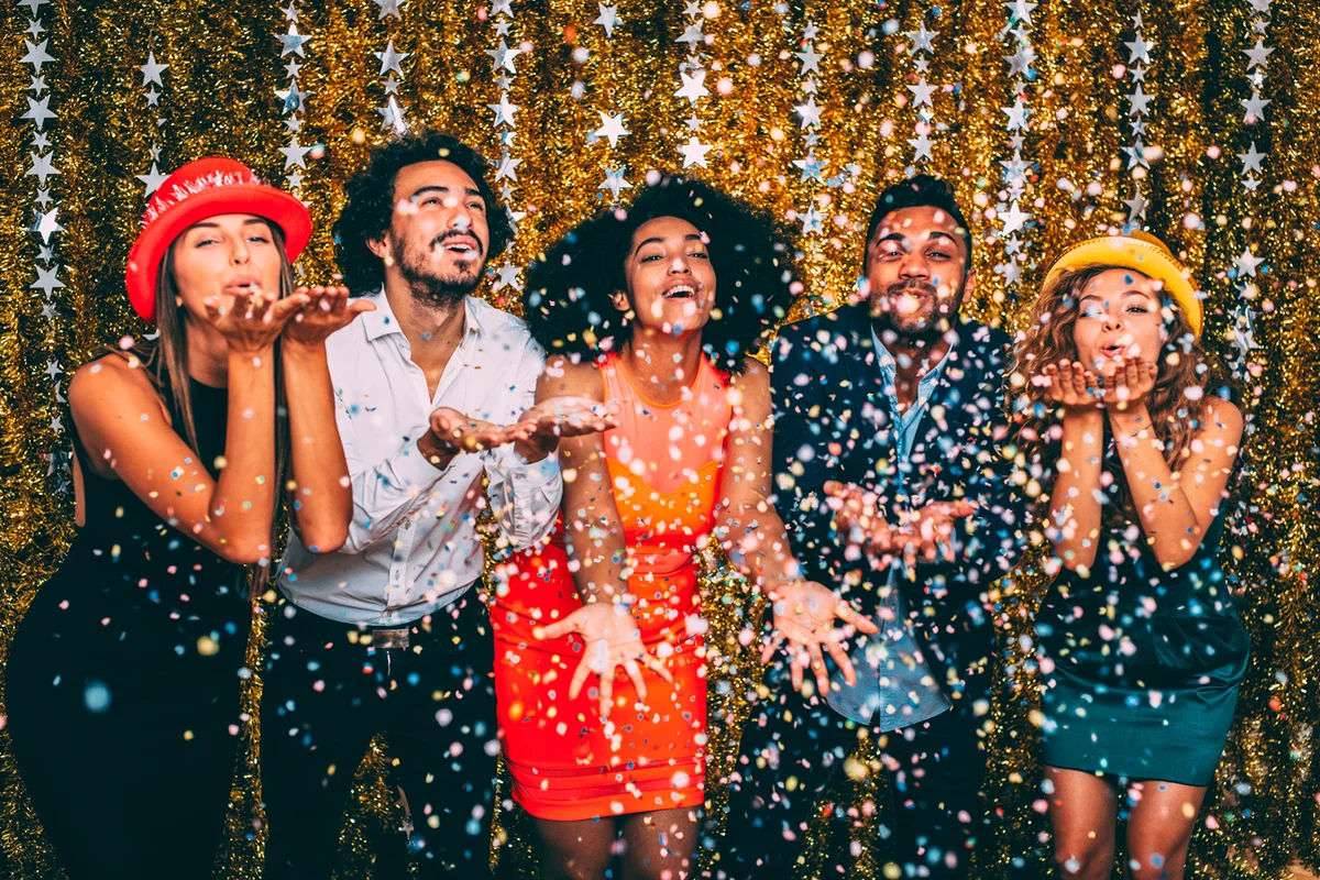 Friends blowing confetti at a new year's party.