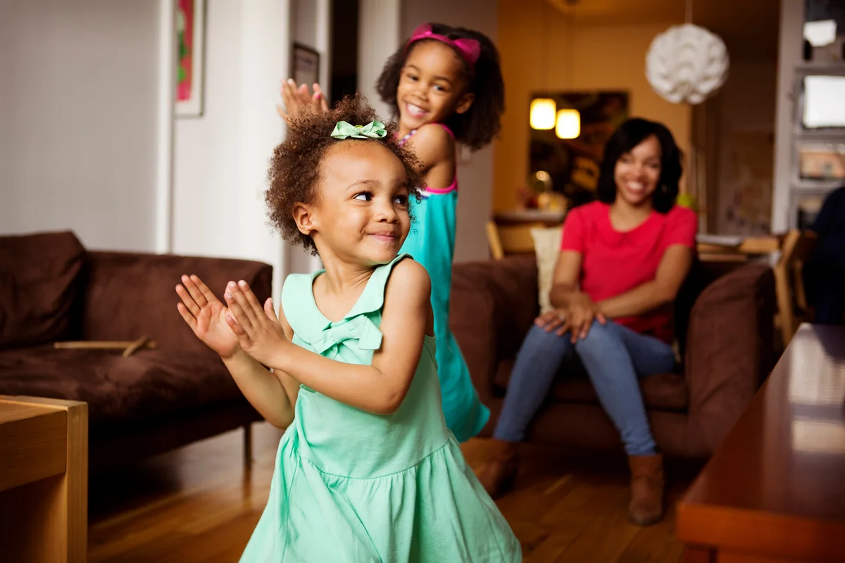 Mother looking at happy daughters dancing in living room