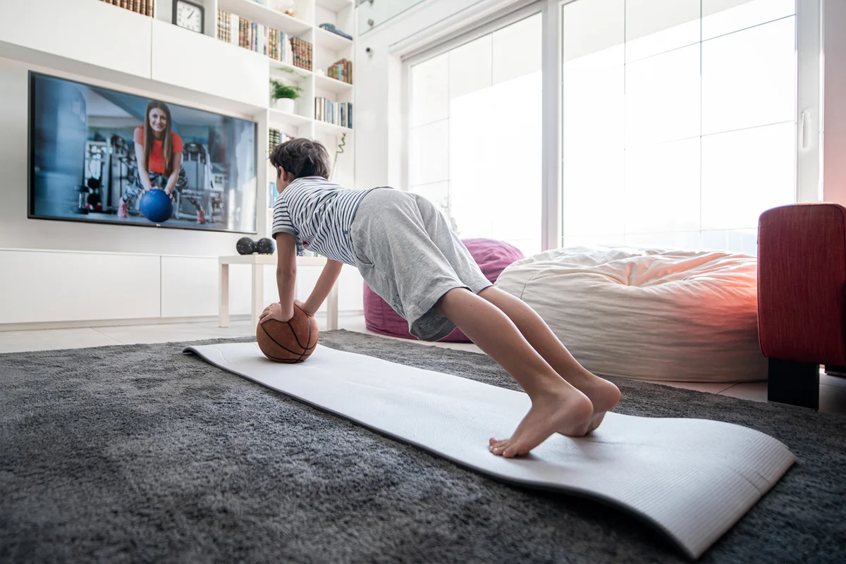 Little boy at home having workout watching online trainer