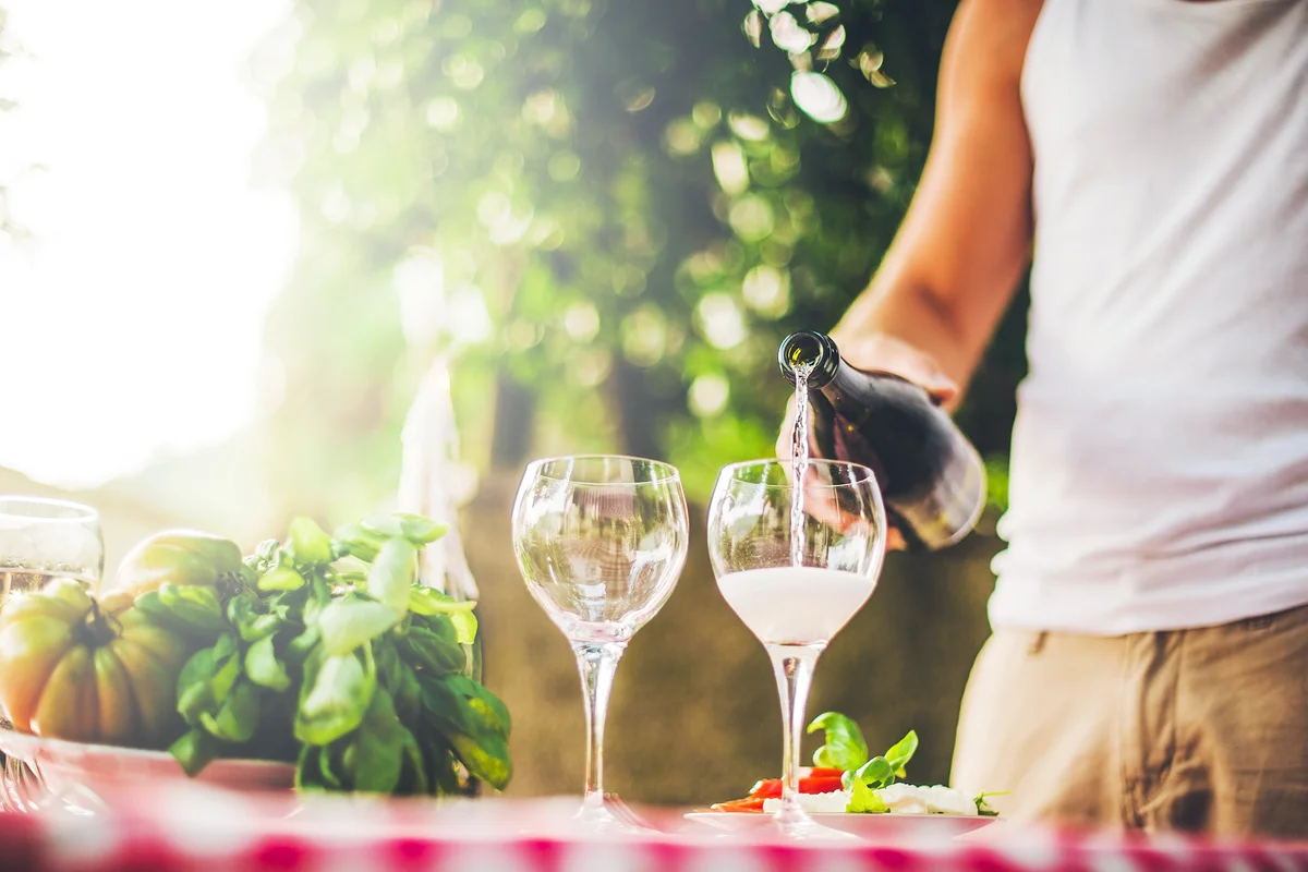 Man pouring sparkling wine at a table outdoors