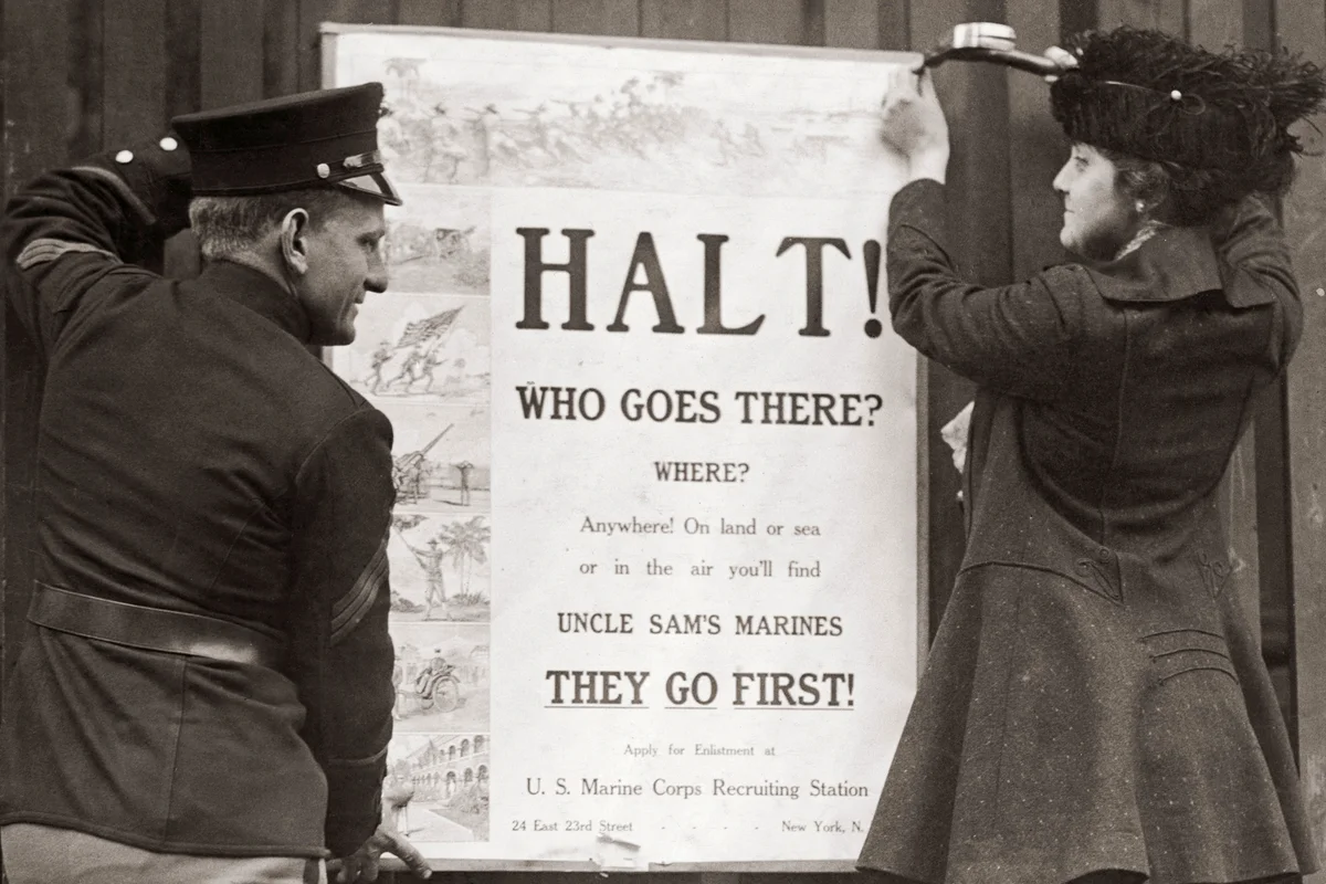 Mrs Davis B. Wills, the wife of a US Marine Corps captain, nails up a recruitment poster for the corps