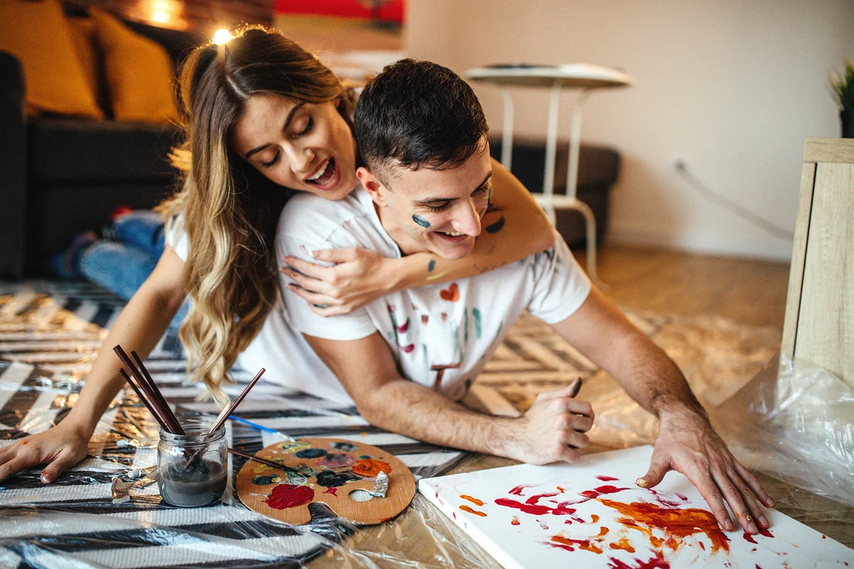 Couple having fun at home, painting on canvas