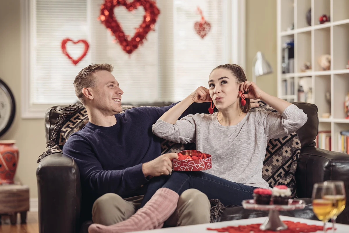 Couple sitting on the sofa at home. Sharing Valentin’s Day gifts
