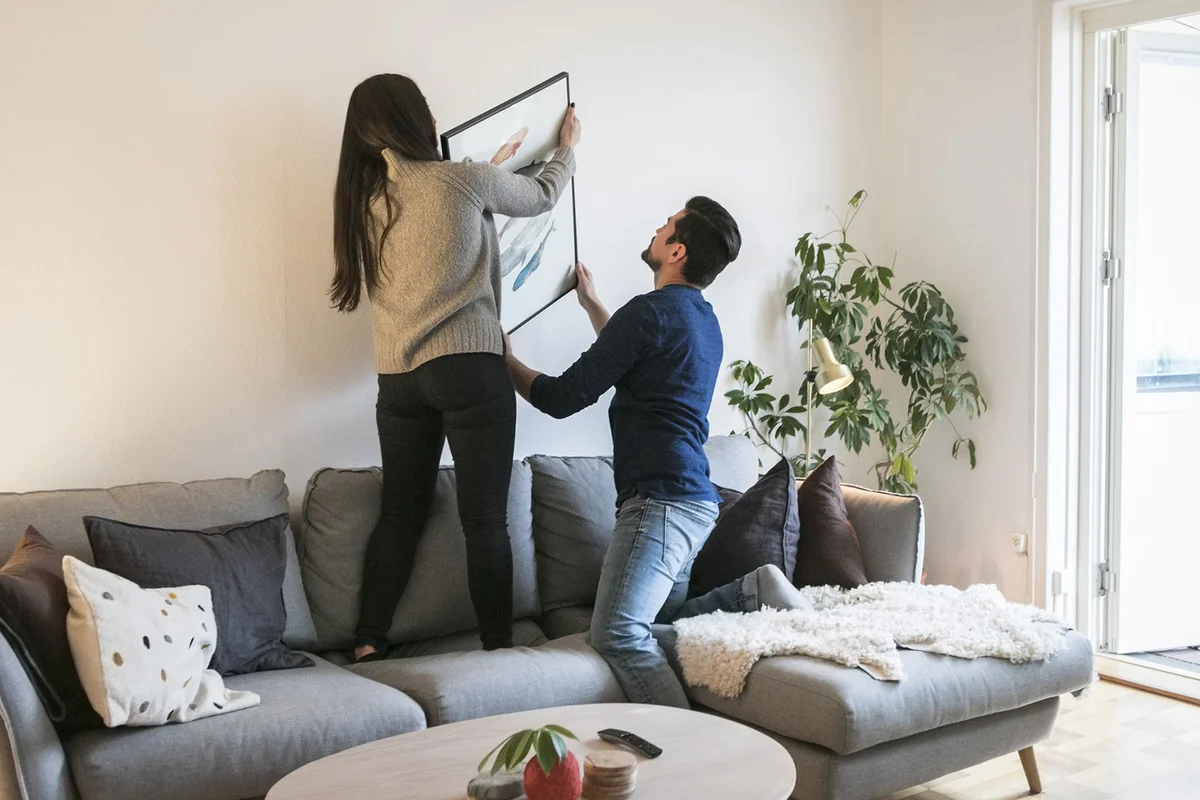 Couple adjusting painting on wall