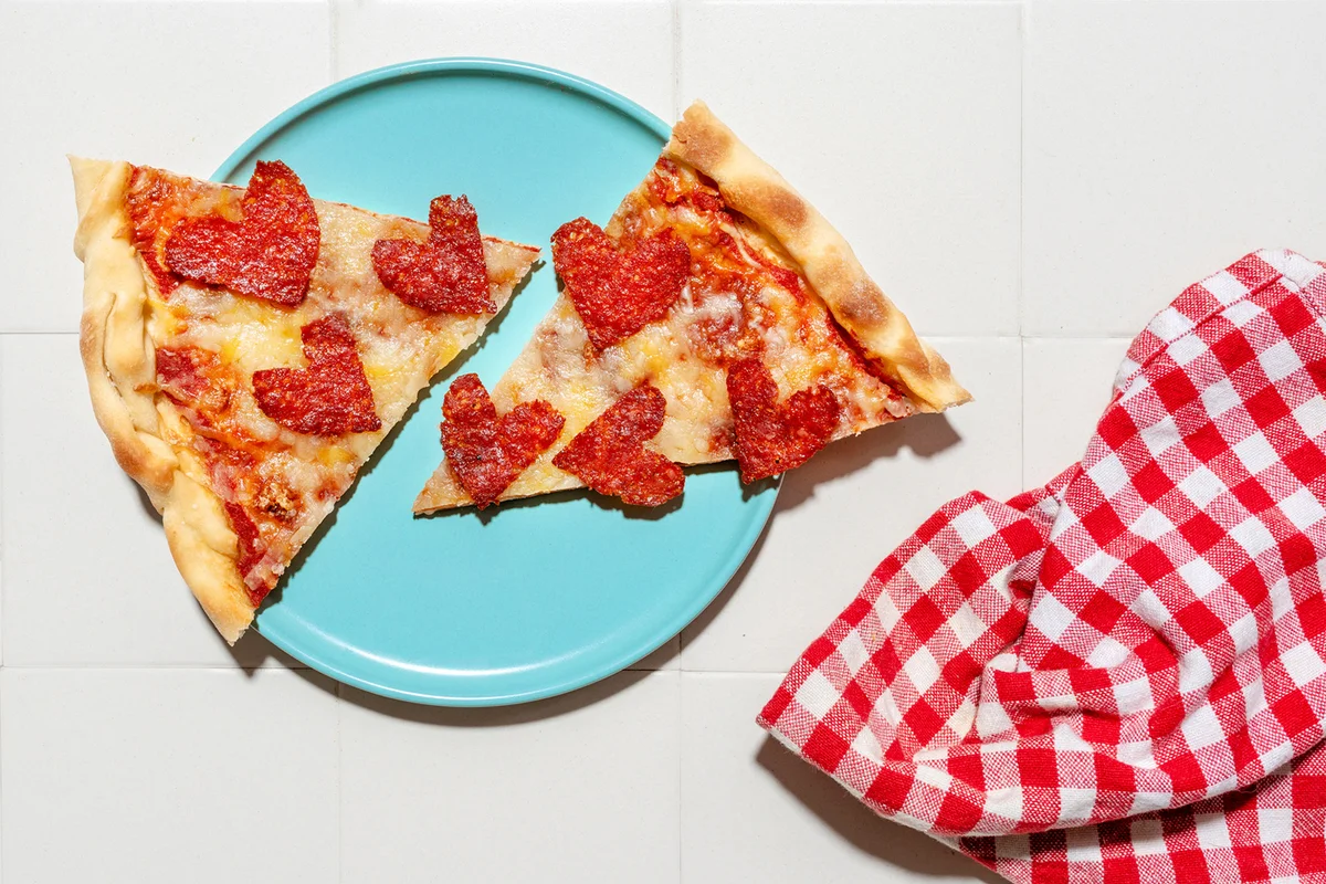 Pizza with pepperoni in heart shapes on blue plate