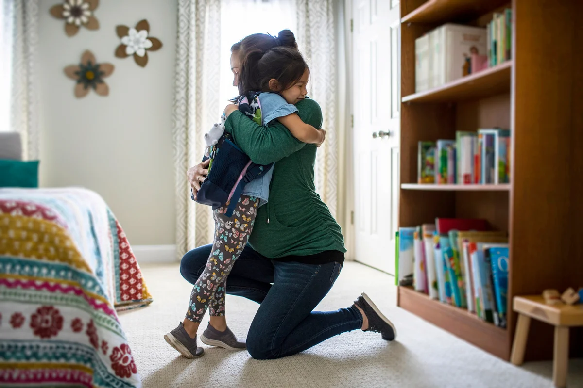 Mother embracing young daughter after school