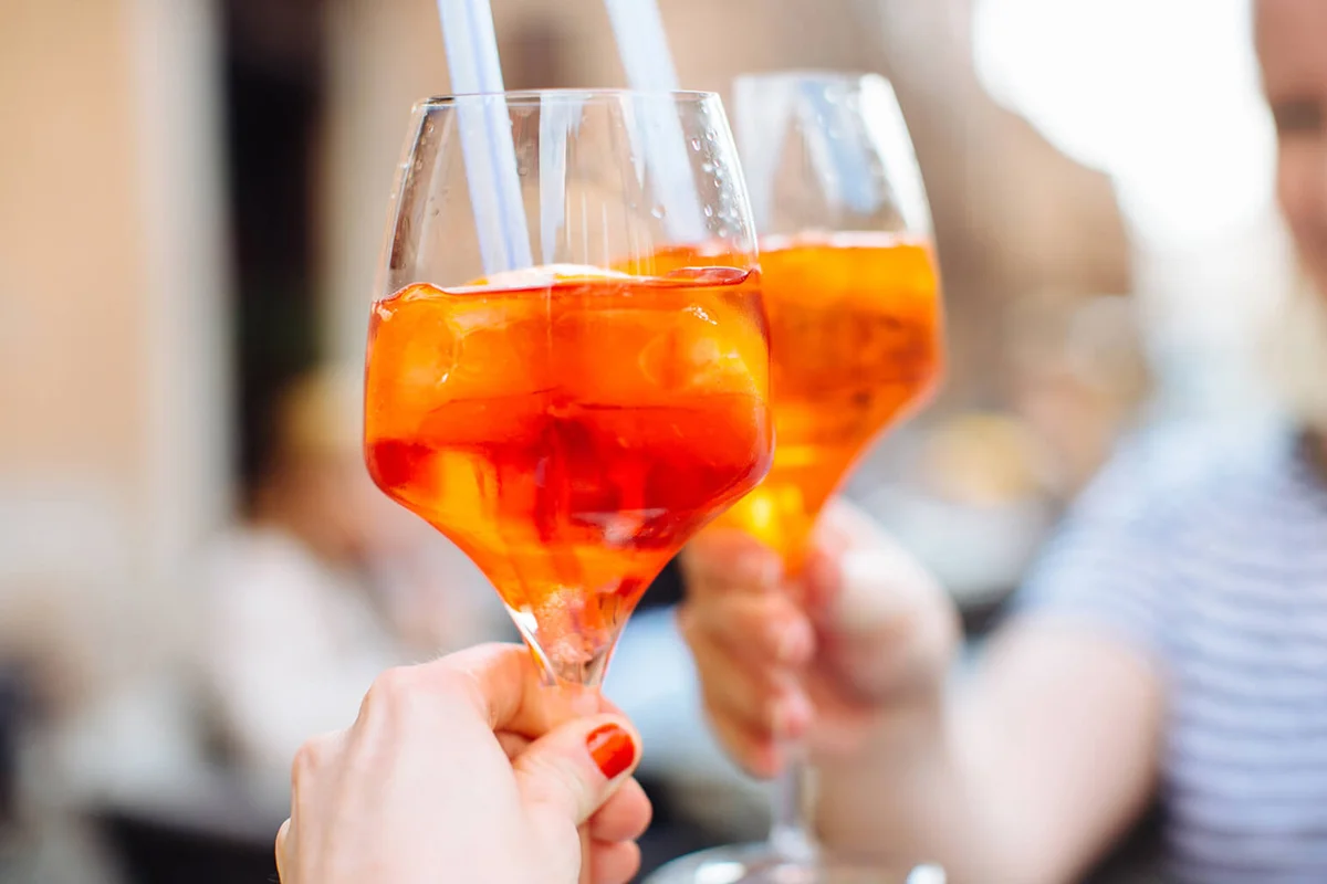 Two women raising a glass of aperol spritz