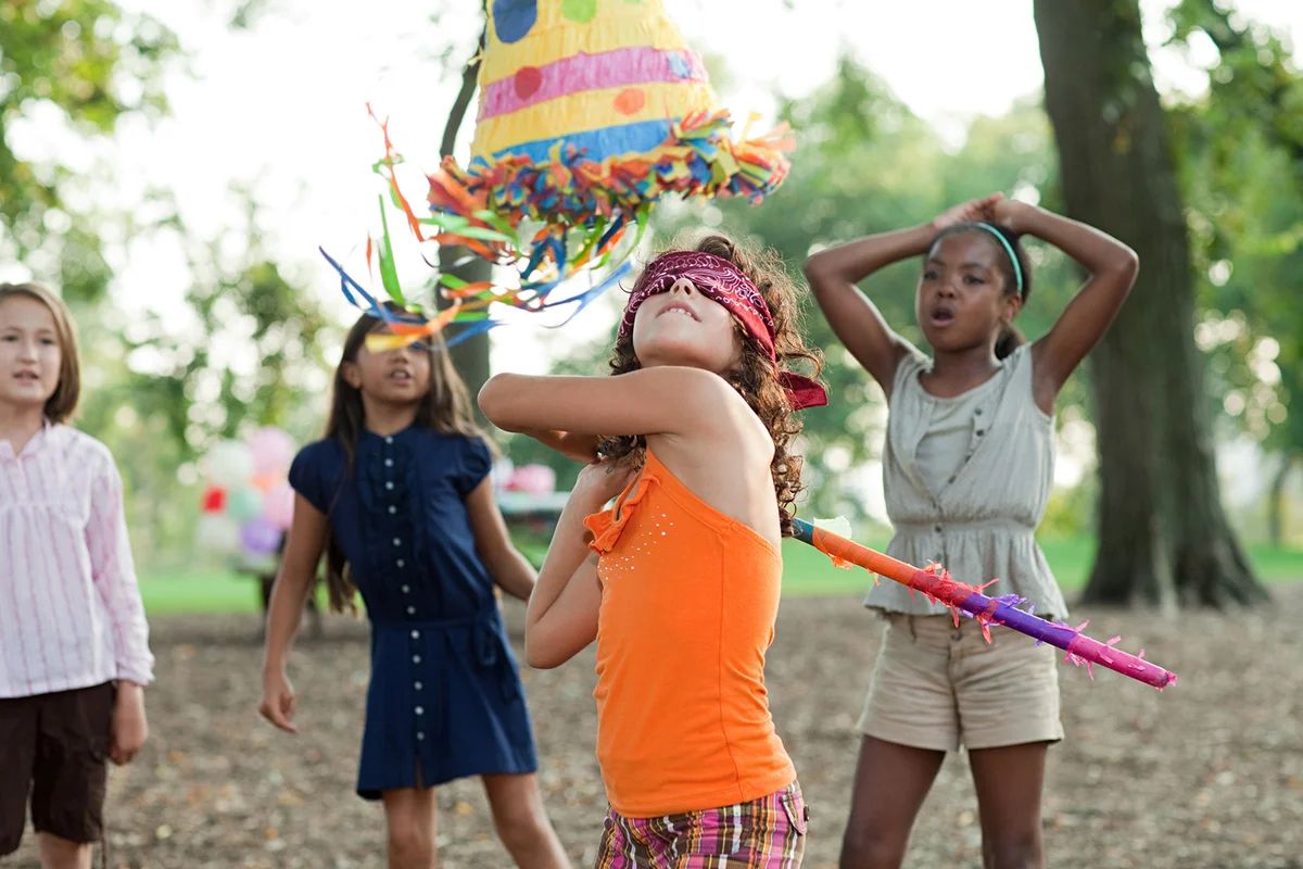 Girl at birthday party hitting piñata
