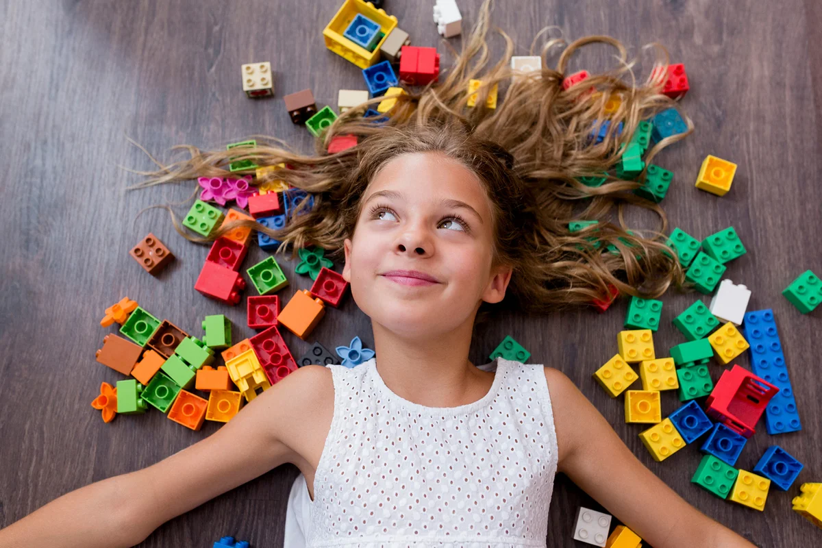 Smiling Girl With Toy Blocks Lying On Floor