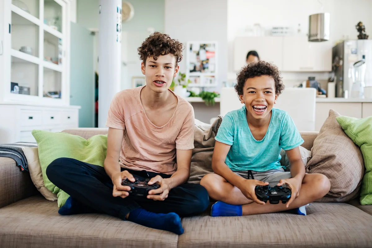 Two Brothers Sitting On Couch Playing Video Games