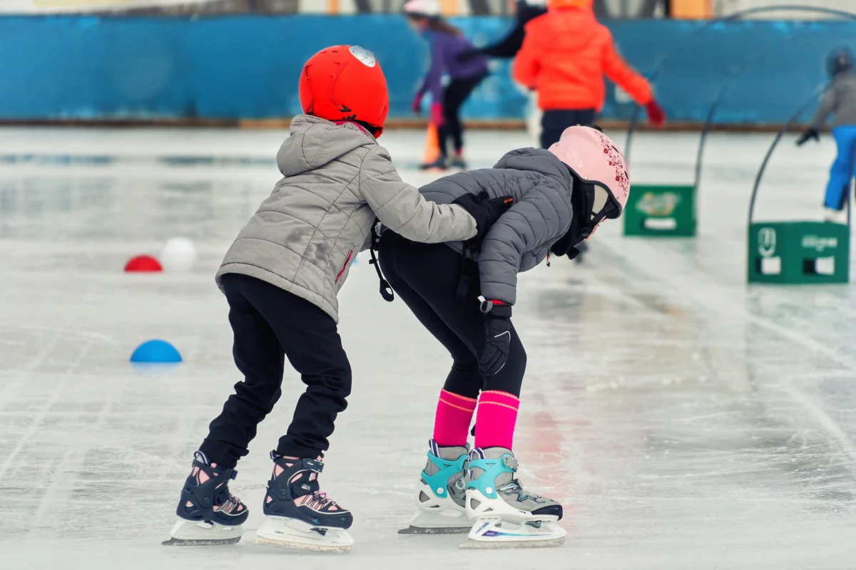 Child's first lessons of skating on the rink