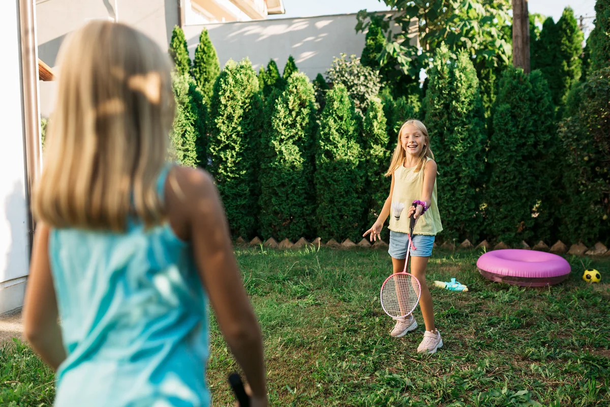 Two sisters playing badminton in their backyard
