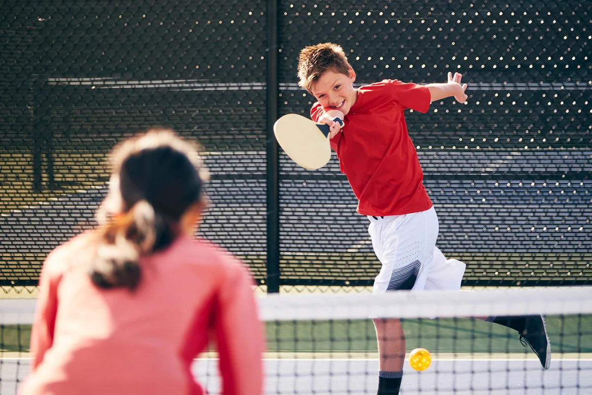 Kids playing pickleball outdoors in a public park