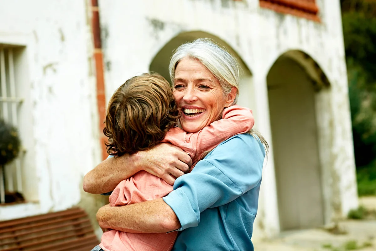 Happy grandmother embracing grandson in yard