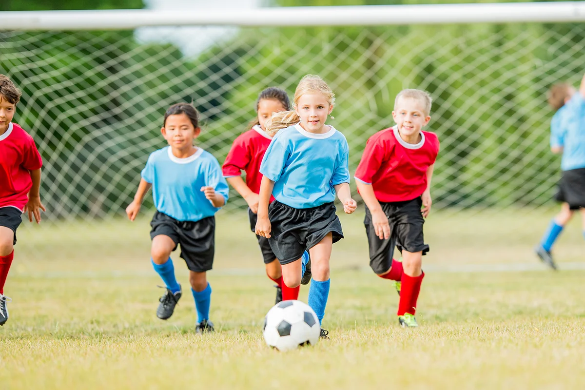 A group of kids are on a soccer field playing a game