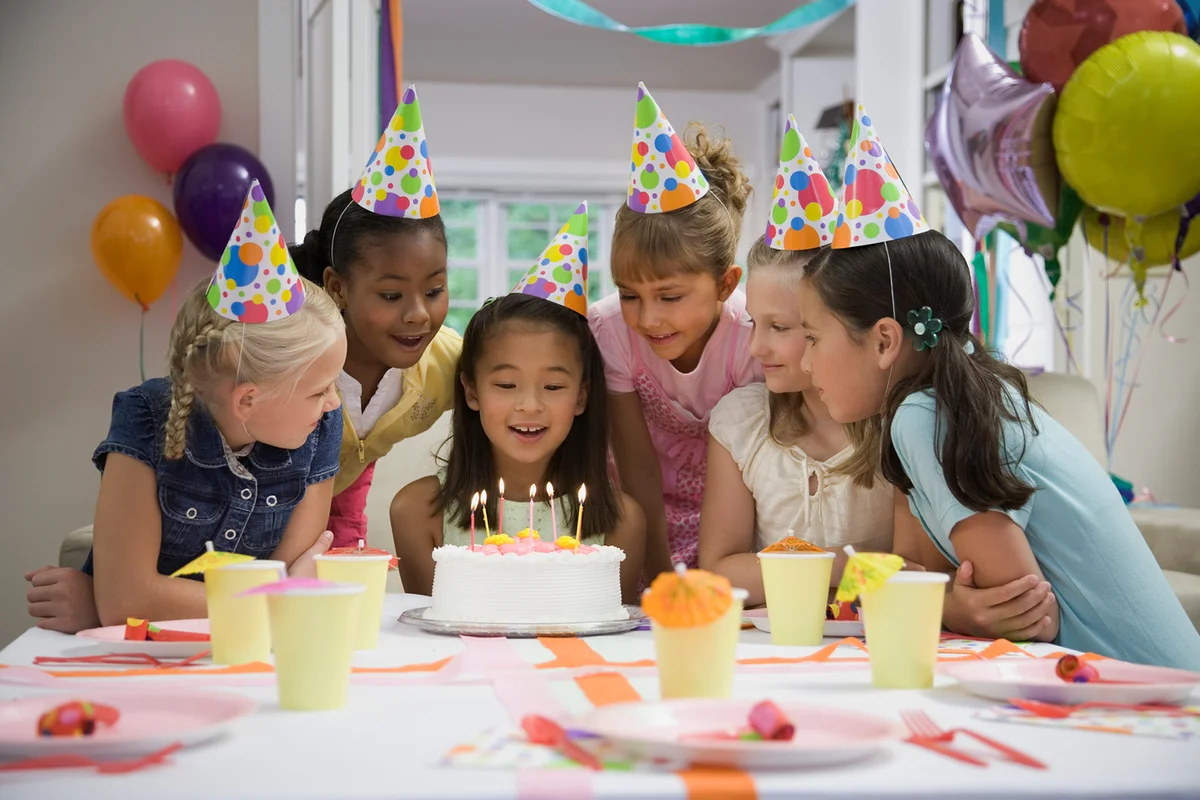 Girl blowing out candles at birthday party