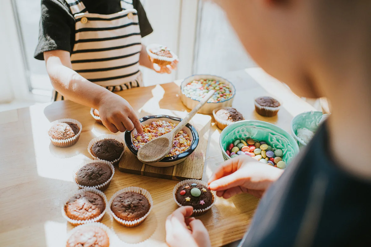 Children decorating cupcakes with sugar toppings