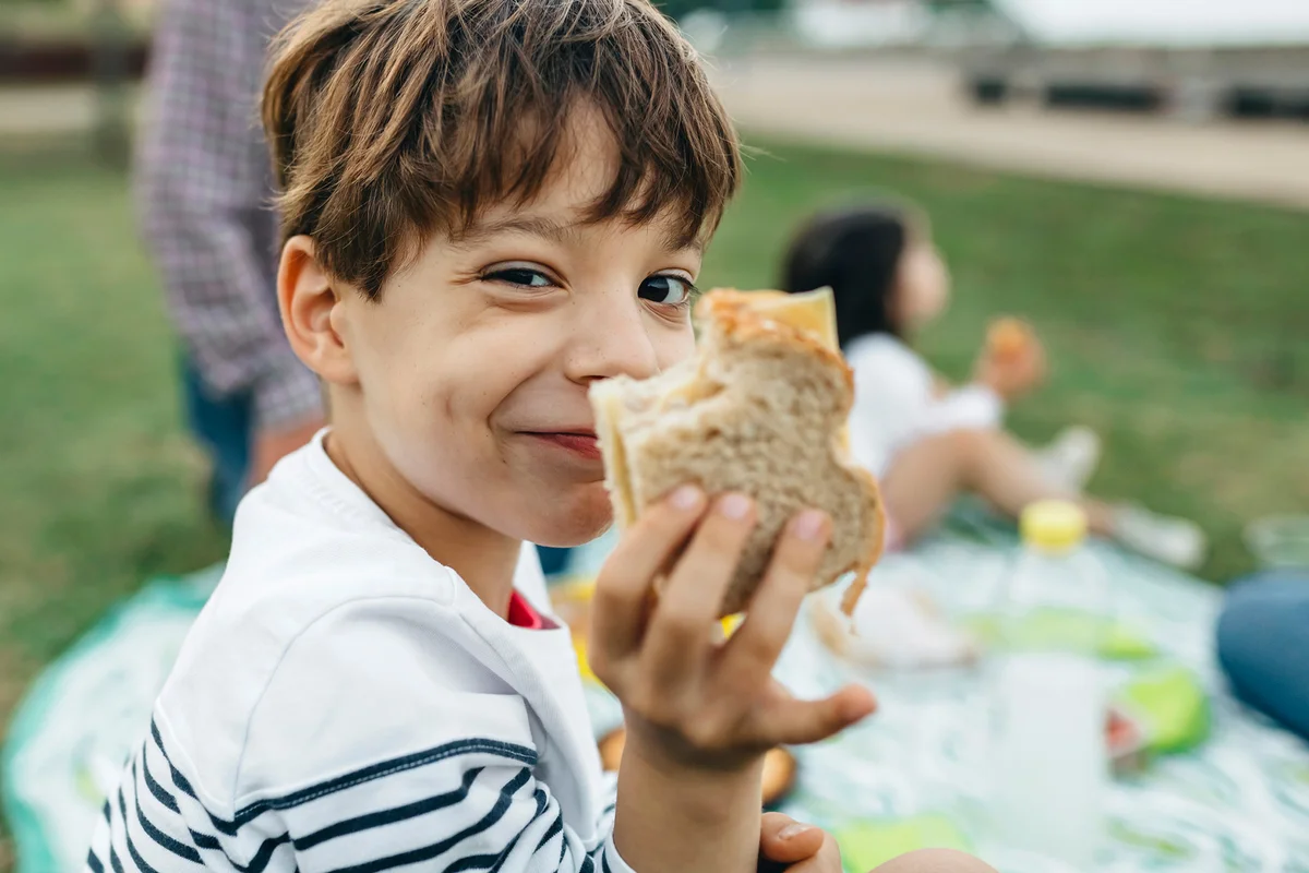 Portrait of smiling boy holding sandwich with his family
