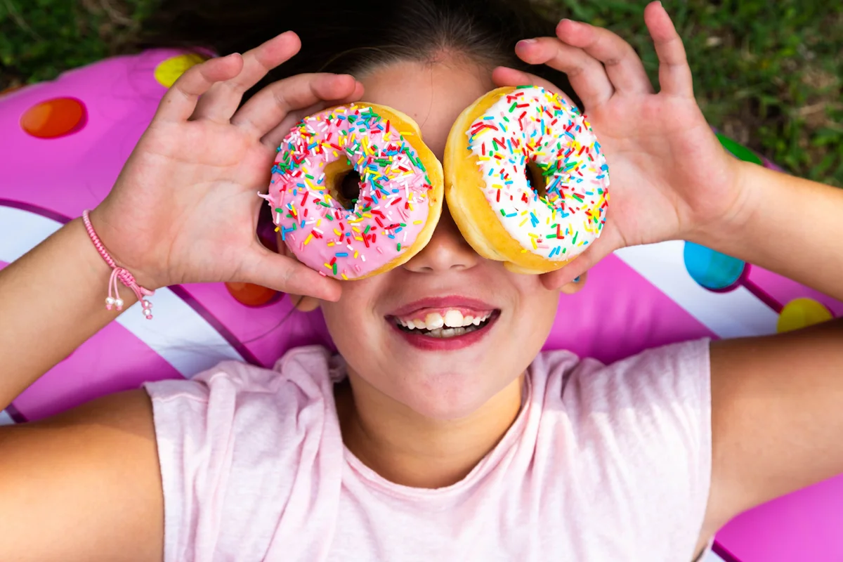 Funny girl using colorful donuts like eyeglasses