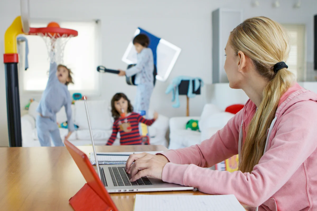 Mother working from home while her kids playing at the background