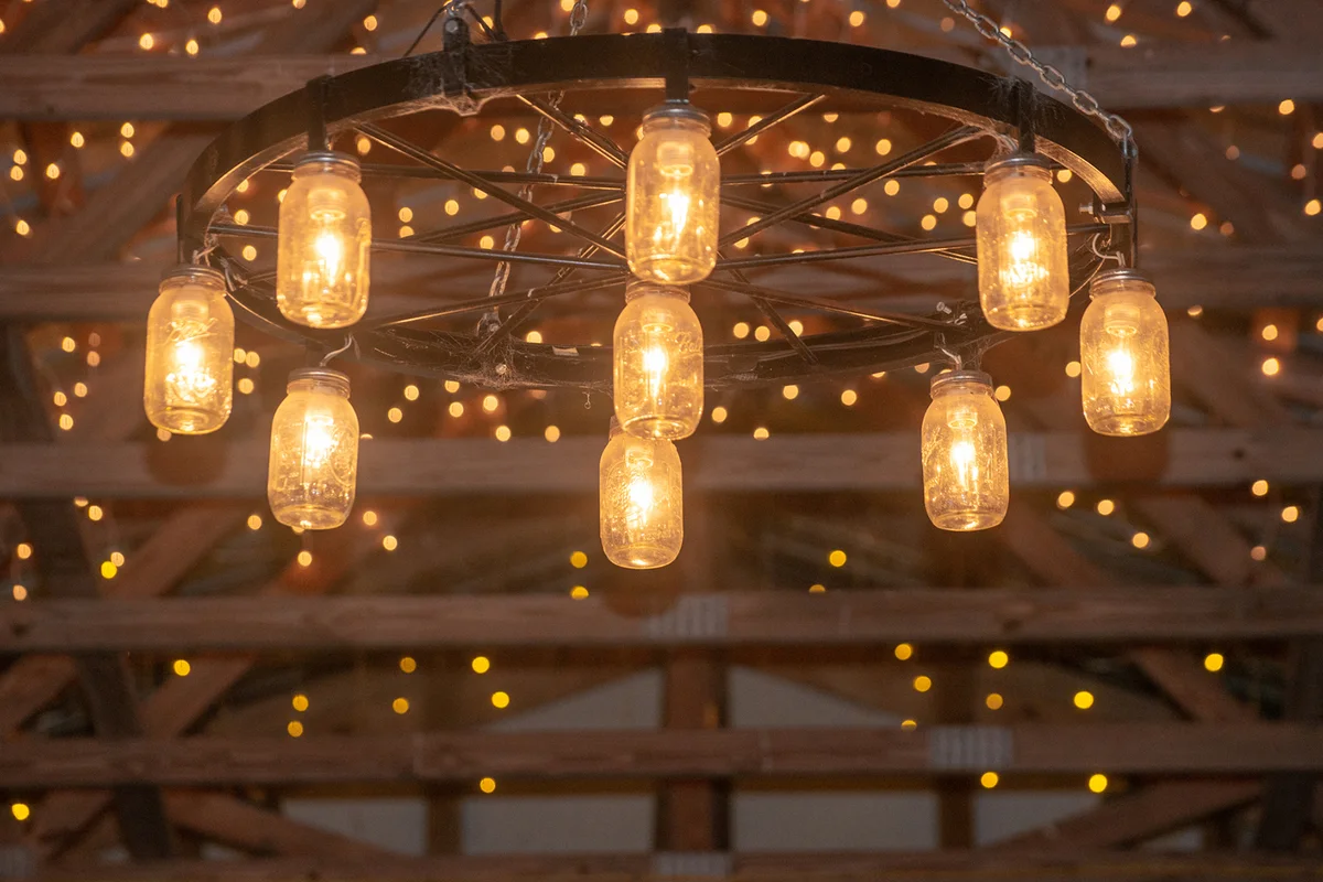 Amazing wagon wheel lamp with mason jar scavos hanging from wood beam barn ceiling