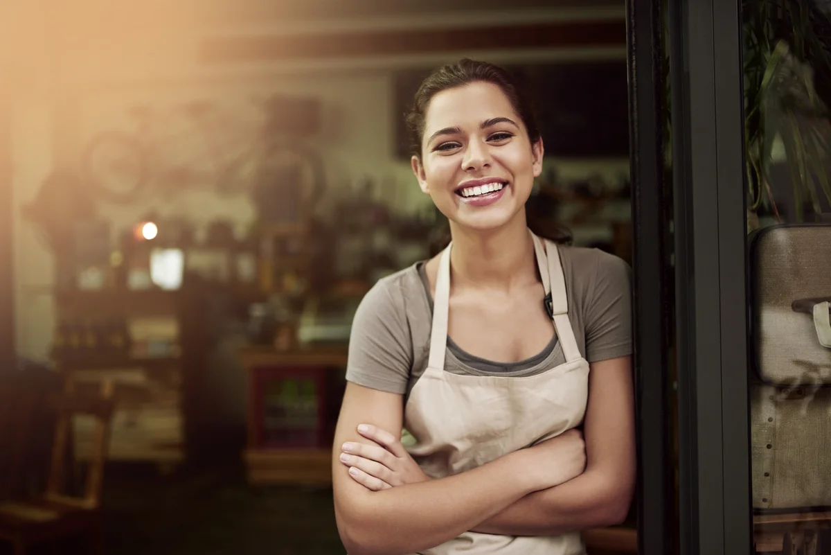proud female business owner standing in front of shop