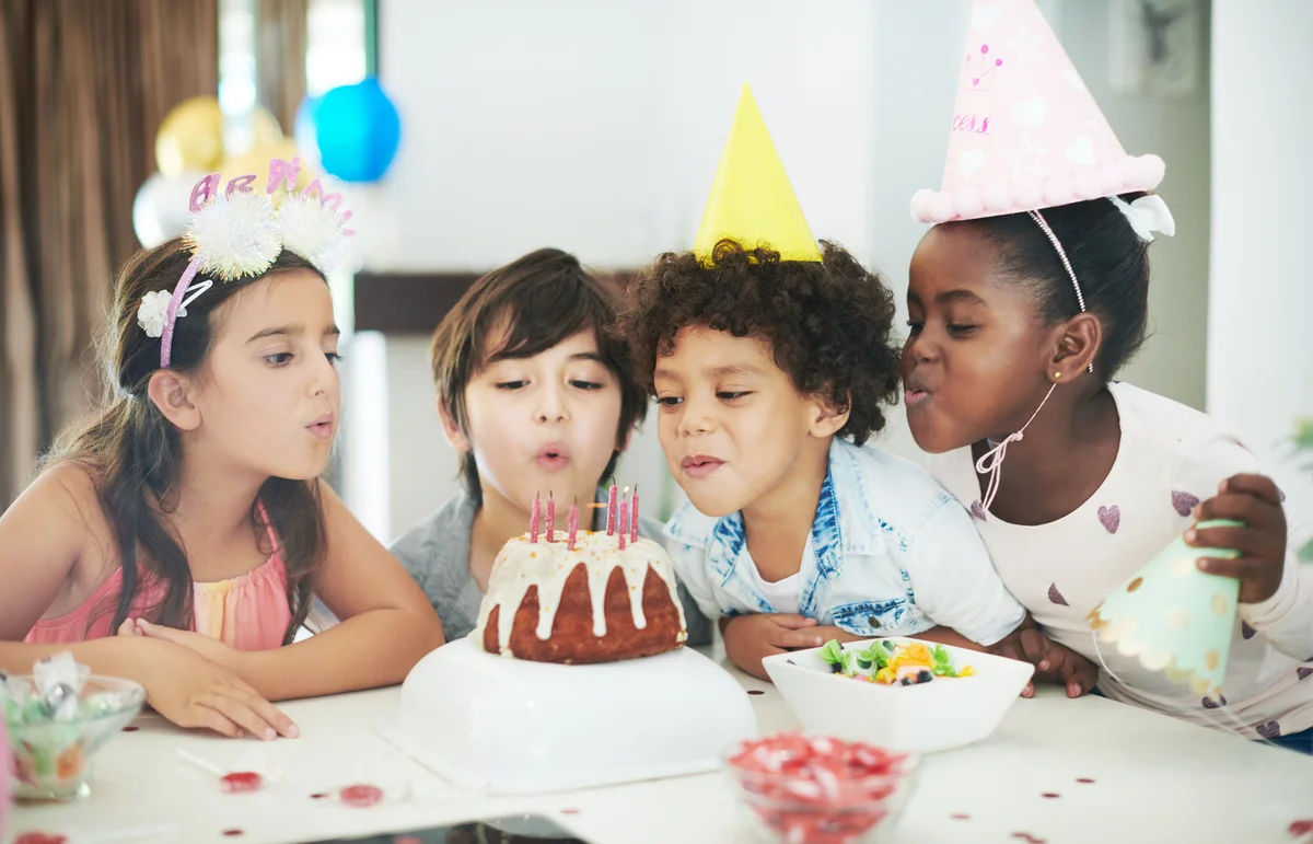 children blowing out candles on birthday cake